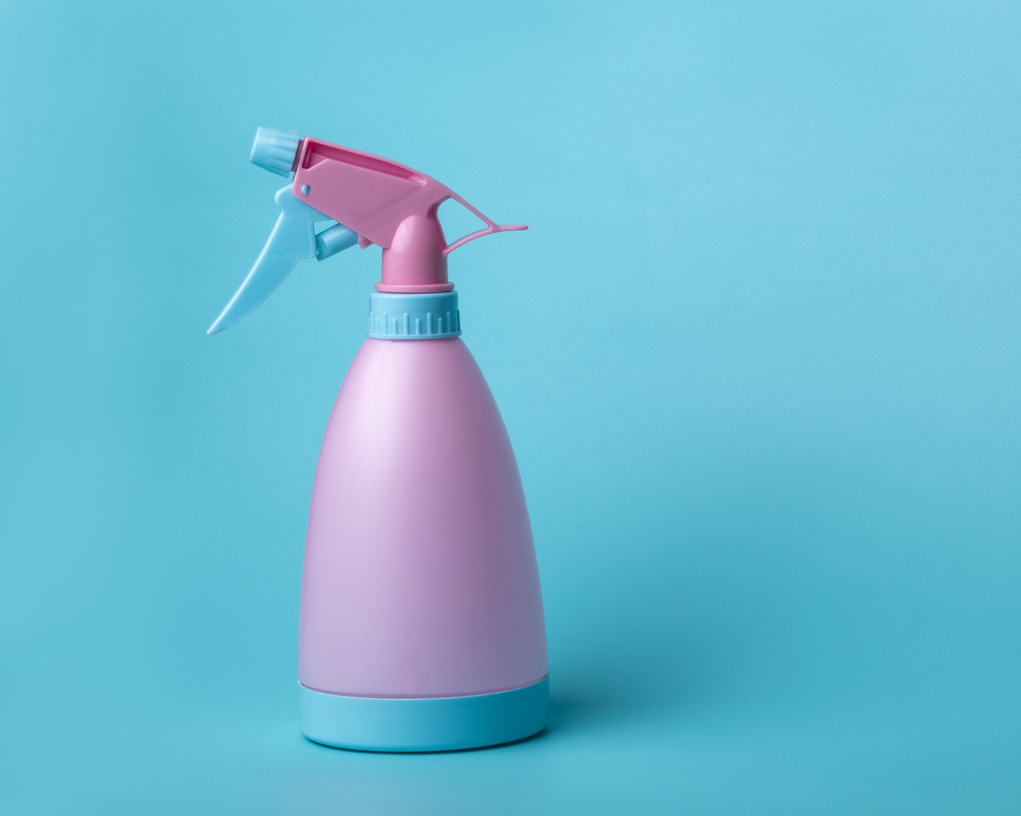 a pink squirt bottle against a light blue background
