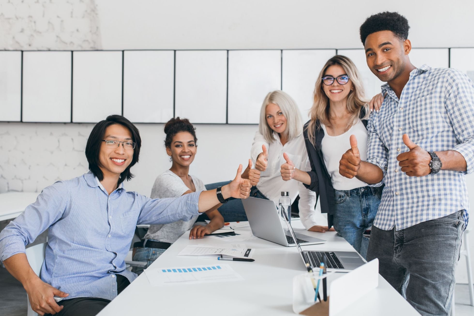 Blonde secretary sitting table while office workers posing with thumbs up indoor portrait happy asian manager trendy shirt smiling conference hall with foreign partners(1)