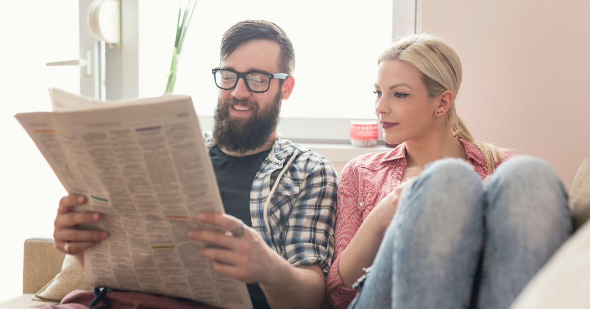Two happy and relaxed people reading a newspaper