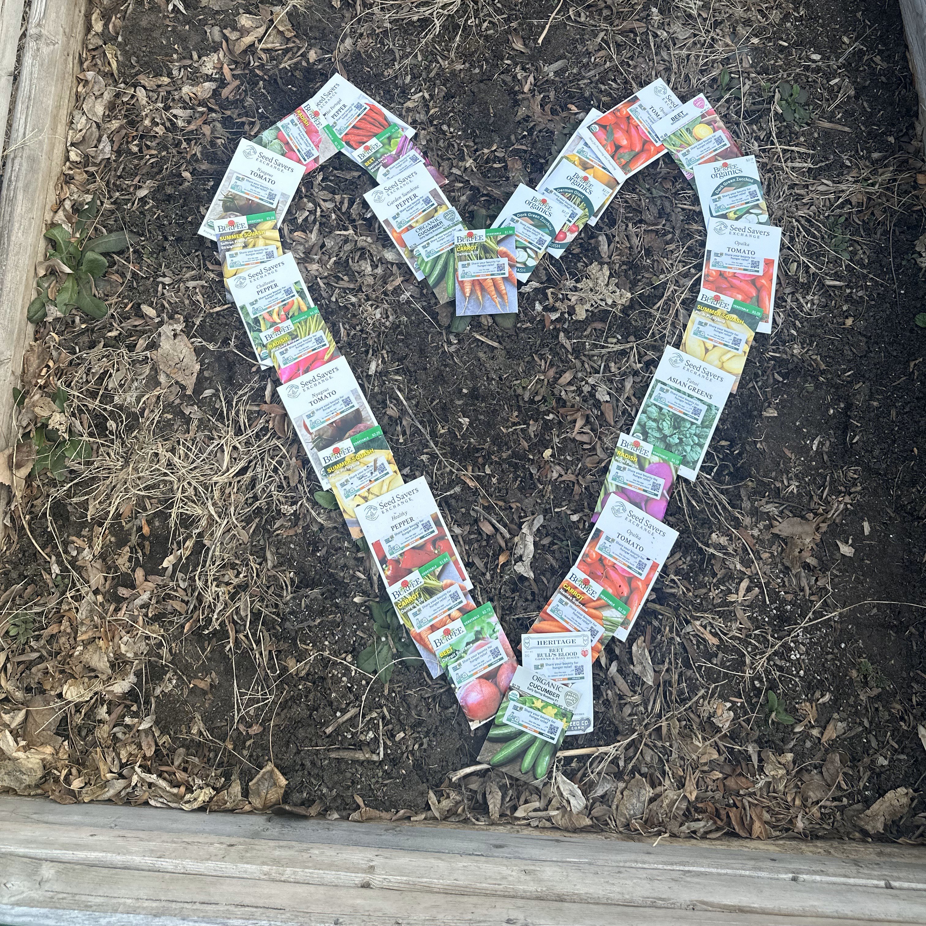 a photo of seed packets in a garden laid out in a heart shape